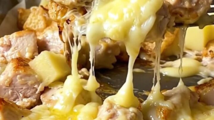 A sheet pan filled with golden roasted potatoes, tender chicken breast chunks, and melted cheese curds.