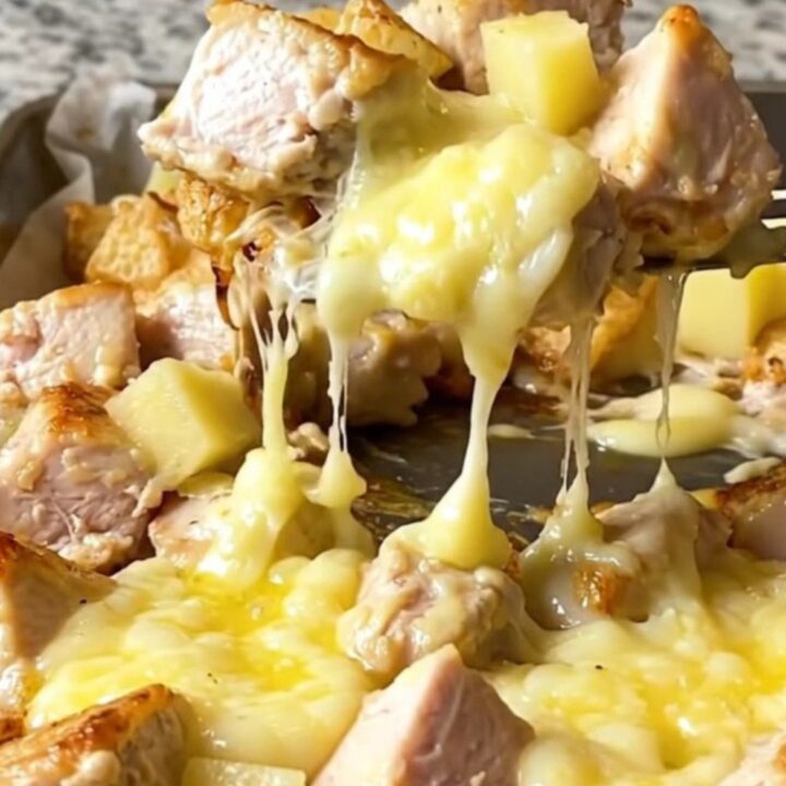 A sheet pan filled with golden roasted potatoes, tender chicken breast chunks, and melted cheese curds.