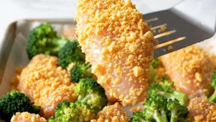 A sheet pan filled with golden-brown cracker-crusted chicken tenders and roasted green broccoli florets.