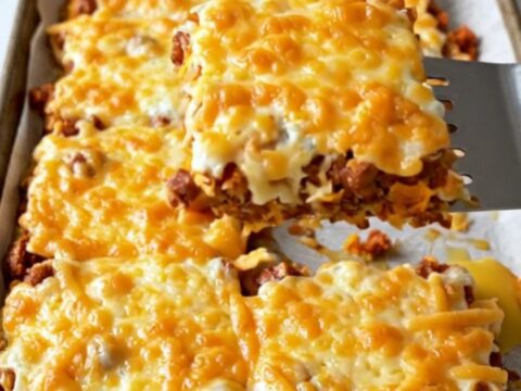 A top-down view of a sheet pan filled with chorizo, sweet potatoes, black beans