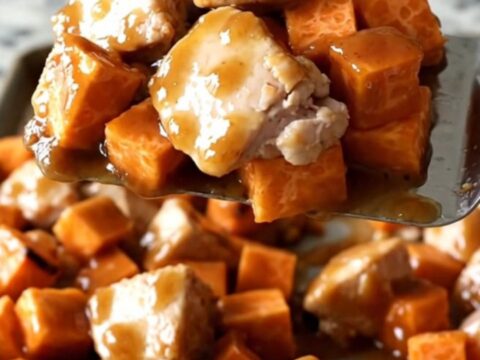 A sheet pan filled with golden roasted sweet potatoes, charred purple onions