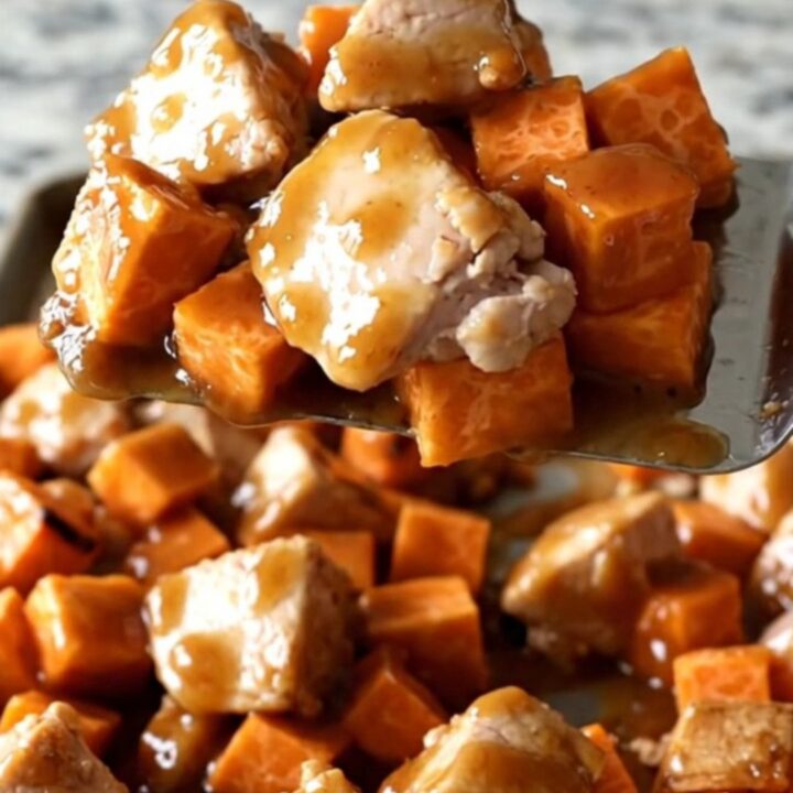 A sheet pan filled with golden roasted sweet potatoes, charred purple onions