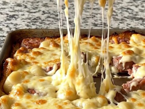 A golden, bubbling sheet pan of Italian sausage, gnocchi, and Brussels sprouts covered in melted cheese.