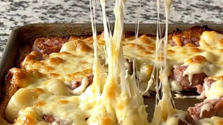 A golden, bubbling sheet pan of Italian sausage, gnocchi, and Brussels sprouts covered in melted cheese.