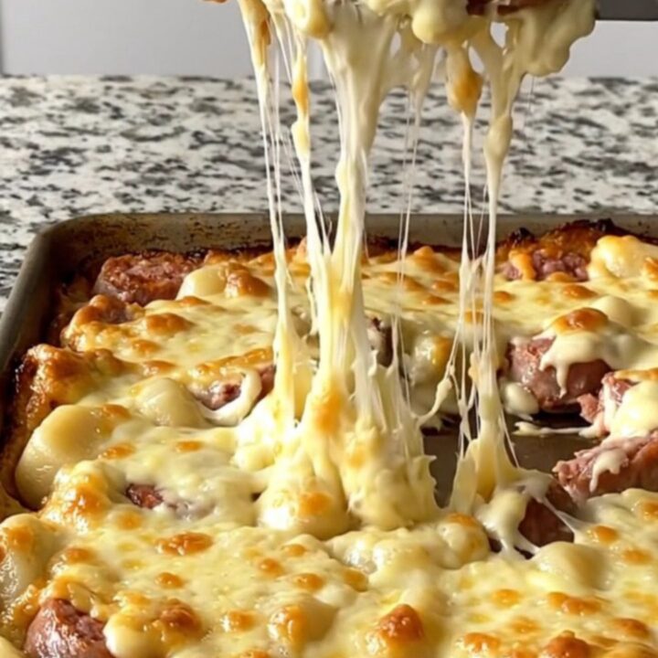 A golden, bubbling sheet pan of Italian sausage, gnocchi, and Brussels sprouts covered in melted cheese.