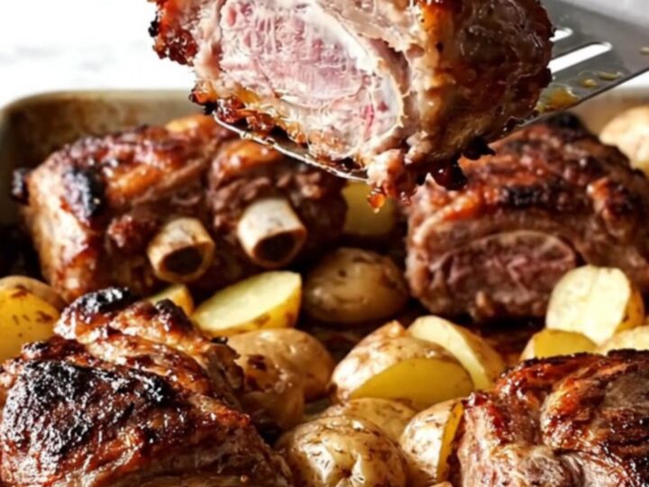 A sheet pan filled with golden roasted baby potatoes, onion wedges, and smoky paprika-rubbed country-style pork ribs.