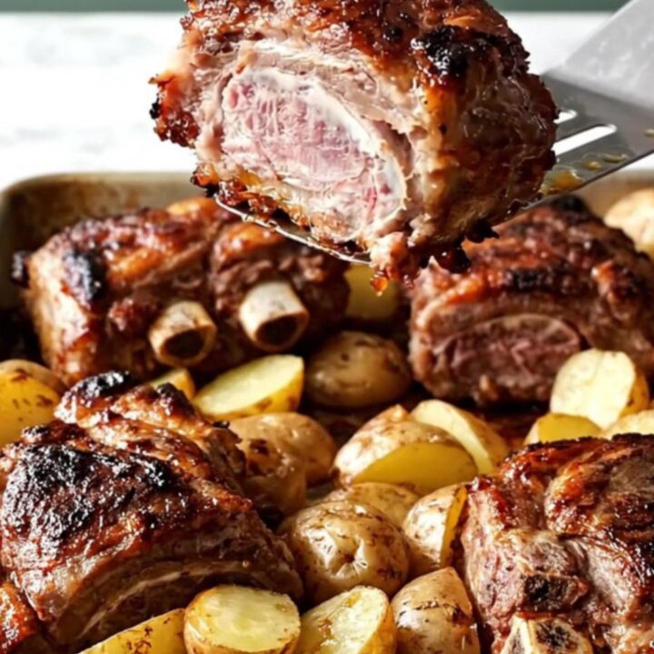 A sheet pan filled with golden roasted baby potatoes, onion wedges, and smoky paprika-rubbed country-style pork ribs.