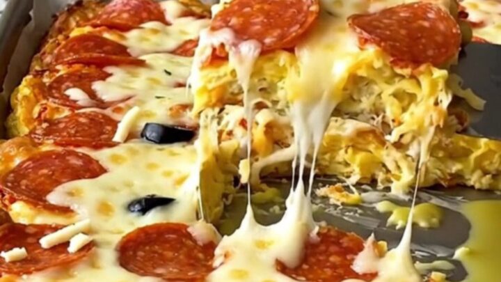 A top-down view of a sheet pan filled with golden-baked pepperoni pizza eggs on a speckled granite countertop.