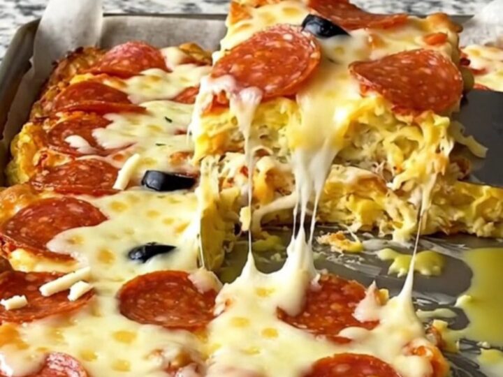 A top-down view of a sheet pan filled with golden-baked pepperoni pizza eggs on a speckled granite countertop.