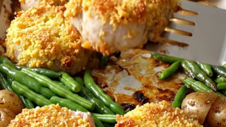 A sheet pan filled with golden-crusted pork tenderloin rounds, roasted baby potatoes, and bright green beans.