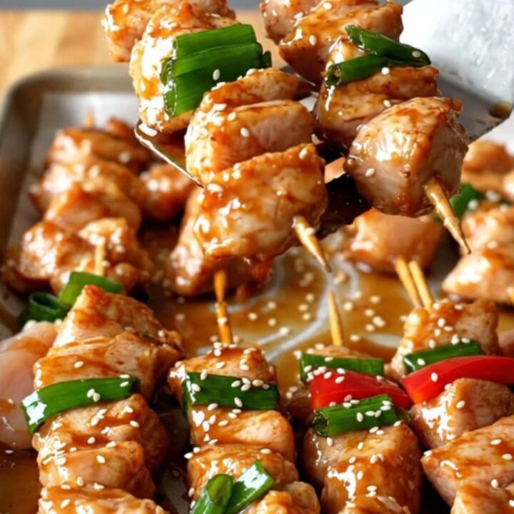 A sheet pan filled with golden-brown chicken chunks, vibrant red peppers, and charred green onions.