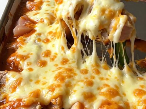 A top-down view of a sheet pan filled with golden roasted chicken, poblano strips, and melted Monterey Jack cheese.