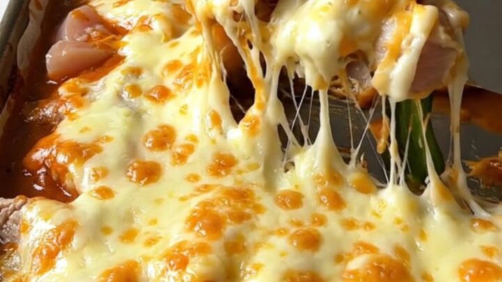 A top-down view of a sheet pan filled with golden roasted chicken, poblano strips, and melted Monterey Jack cheese.