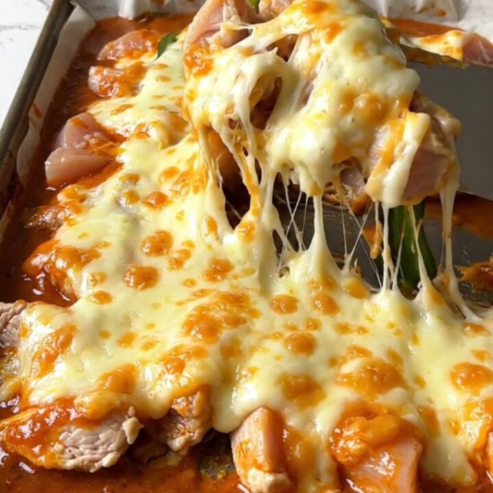 A top-down view of a sheet pan filled with golden roasted chicken, poblano strips, and melted Monterey Jack cheese.