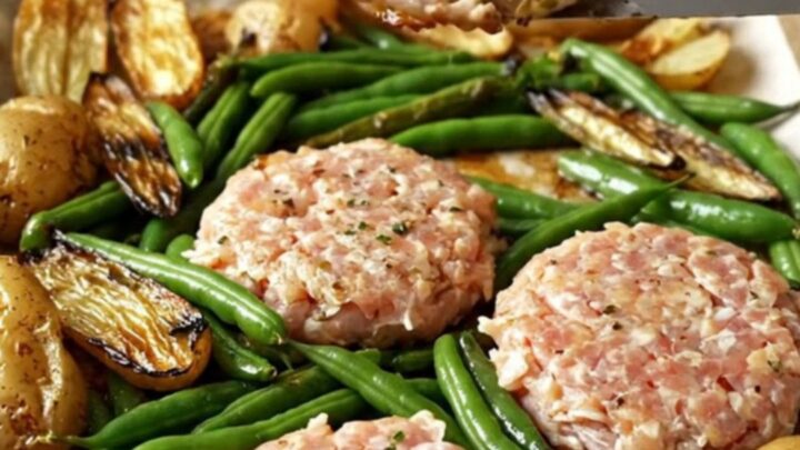 A sheet pan filled with golden-brown turkey patties, roasted baby potatoes, and blistered green beans.