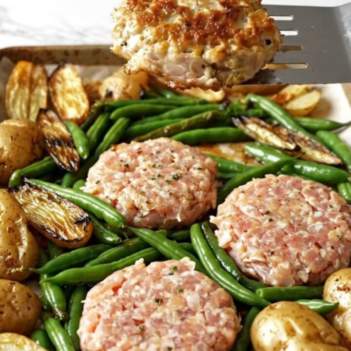 A sheet pan filled with golden-brown turkey patties, roasted baby potatoes, and blistered green beans.