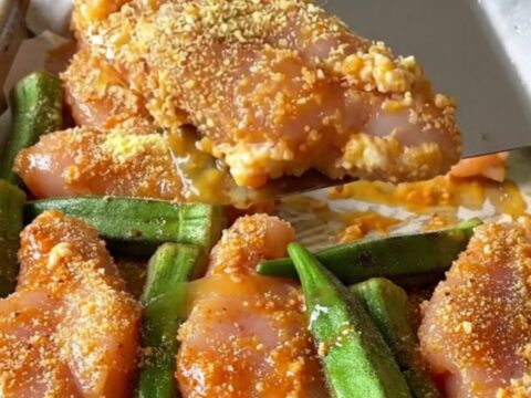Crispy cornmeal crusted chicken tenders and roasted okra on a parchment-lined sheet pan.