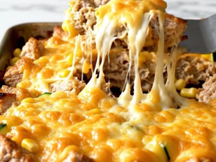 A sheet pan filled with golden roasted chicken, zucchini, and corn topped with melted Monterey Jack cheese.