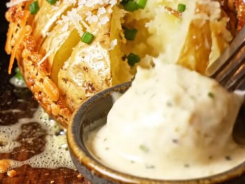 Close-up of a crispy Garlic Parmesan Hasselback Potato with golden ridges and melted cheese.