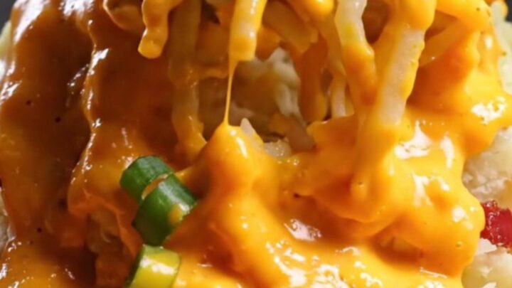 A towering mashed potato volcano in a cast-iron skillet with molten cheddar cheese sauce overflowing from the center.