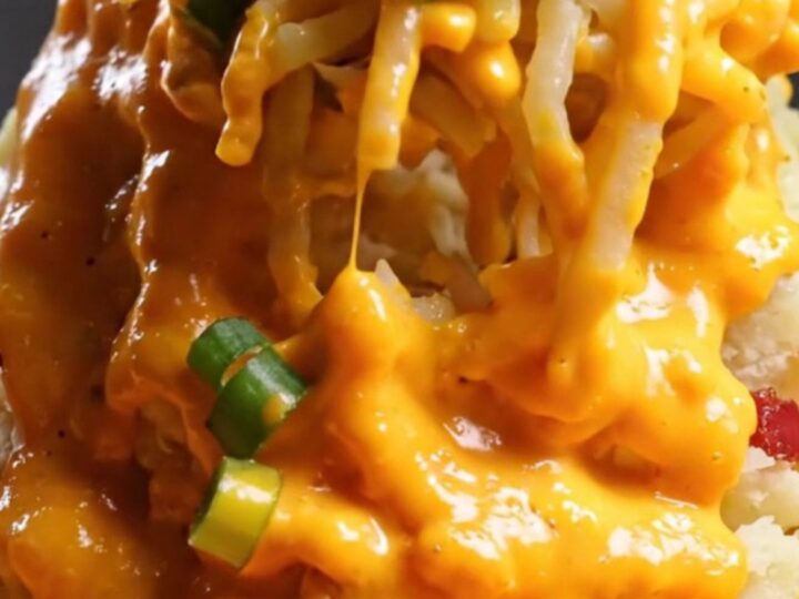 A towering mashed potato volcano in a cast-iron skillet with molten cheddar cheese sauce overflowing from the center.
