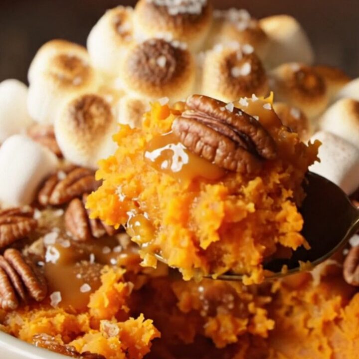 A golden, toasted marshmallow-topped sweet potato casserole in a ceramic dish.
