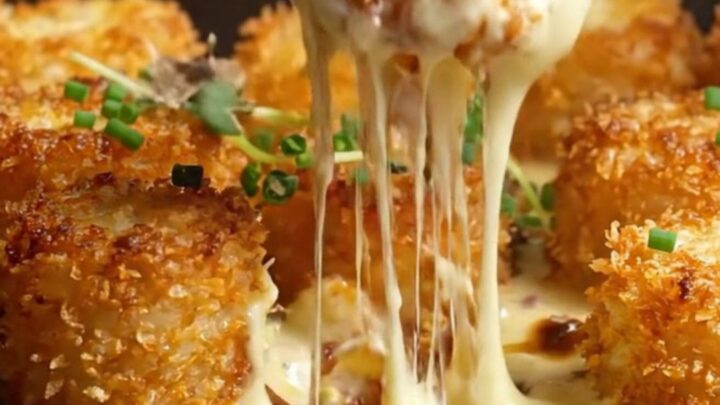 A ceramic gratin dish filled with golden tater tots in a rich, bubbling truffle Gruyère cheese sauce.
