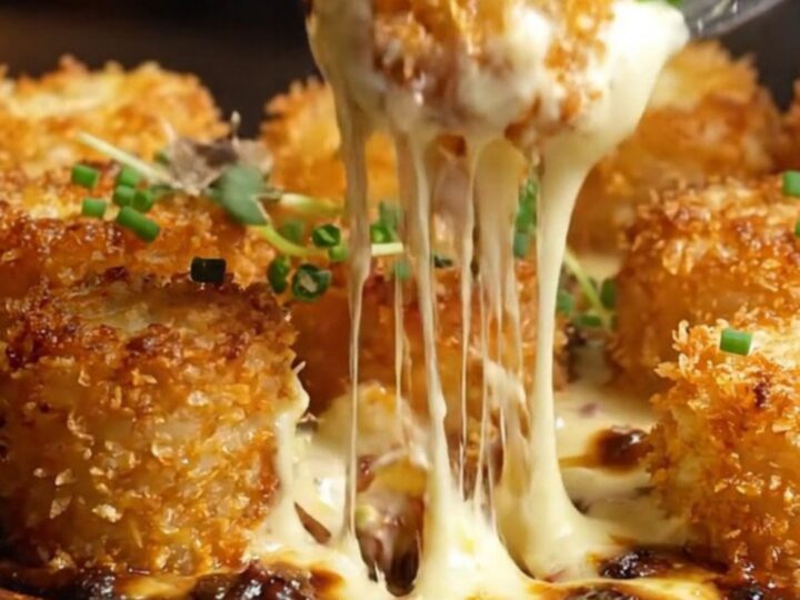 A ceramic gratin dish filled with golden tater tots in a rich, bubbling truffle Gruyère cheese sauce.