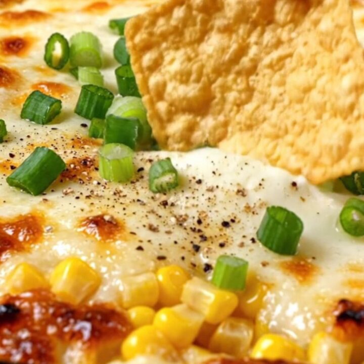 A large spoon lifting a massive scoop of Korean cheese corn from a sizzling cast-iron skillet with a long cheese pull.