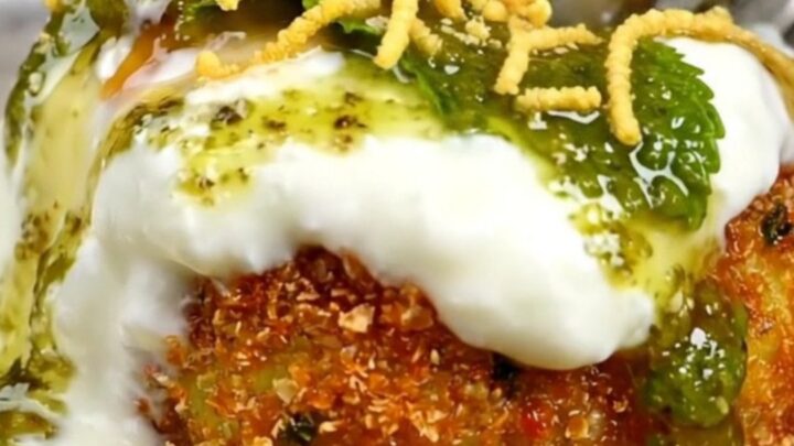 A close-up of a golden, crispy stuffed Aloo Tikki with a crack in the crust revealing a steaming pea and paneer filling.