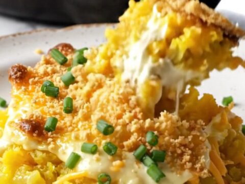 A golden, bubbly Southern yellow squash casserole in a cast-iron skillet with a crispy Ritz cracker topping.