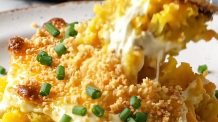 A golden, bubbly Southern yellow squash casserole in a cast-iron skillet with a crispy Ritz cracker topping.