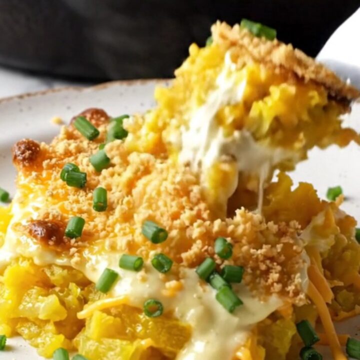 A golden, bubbly Southern yellow squash casserole in a cast-iron skillet with a crispy Ritz cracker topping.