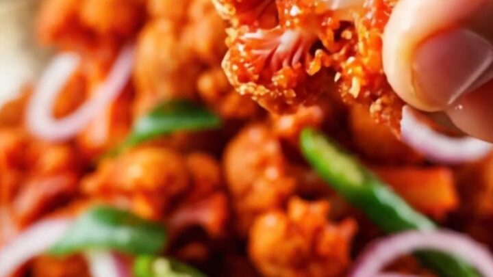 A vibrant bowl of crispy golden-brown Gobi 65 topped with fresh lime wedges and sliced onion rings.