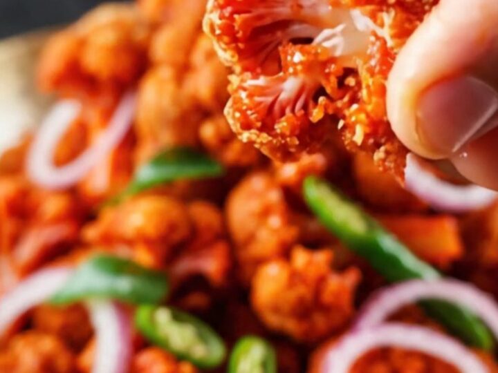 A vibrant bowl of crispy golden-brown Gobi 65 topped with fresh lime wedges and sliced onion rings.