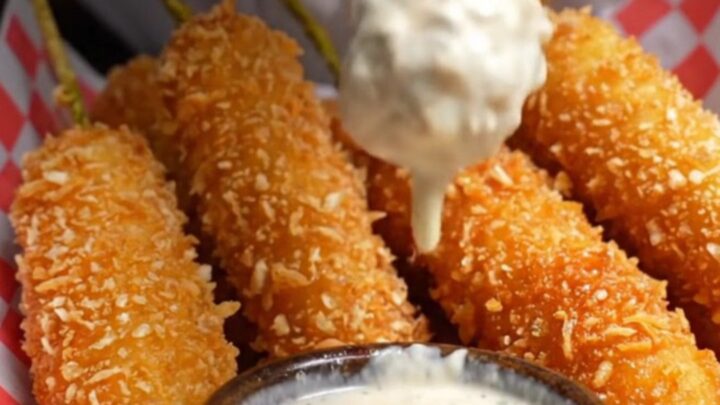 A golden, panko-crusted fried pickle spear being pulled in half, showing a crunchy exterior and a juicy dill center.