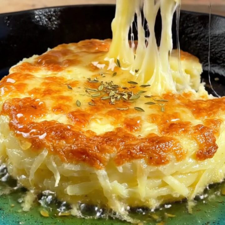 A crispy golden-brown potato and cheese cake in a cast-iron skillet, drizzled with honey and lemon.