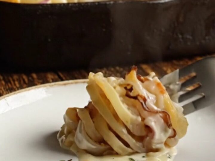 A close-up shot of a creamy potato and turnip gratin with a bubbly, blistered golden white cheddar crust.