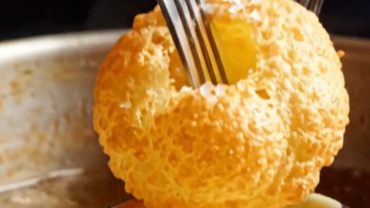 Golden, perfectly puffed hollow potato pillows arranged on a white plate with a side of creamy bearnaise sauce.