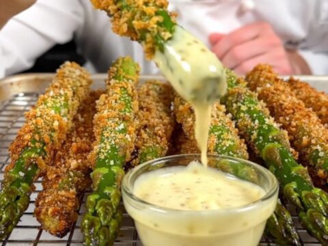 A close-up of crispy Parmesan-crusted asparagus spears on a wire rack, golden-brown and ready to serve.
