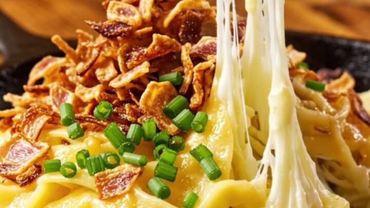 A steaming, golden-brown portion of Käsespätzle topped with crispy shallots and fresh chives.