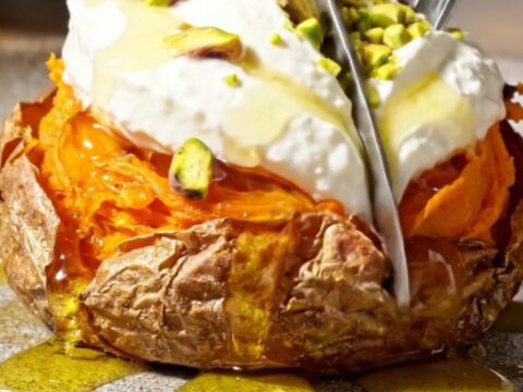 Crispy smashed sweet potato rounds topped with creamy whipped feta, hot honey, and crushed pistachios on a serving platter.
