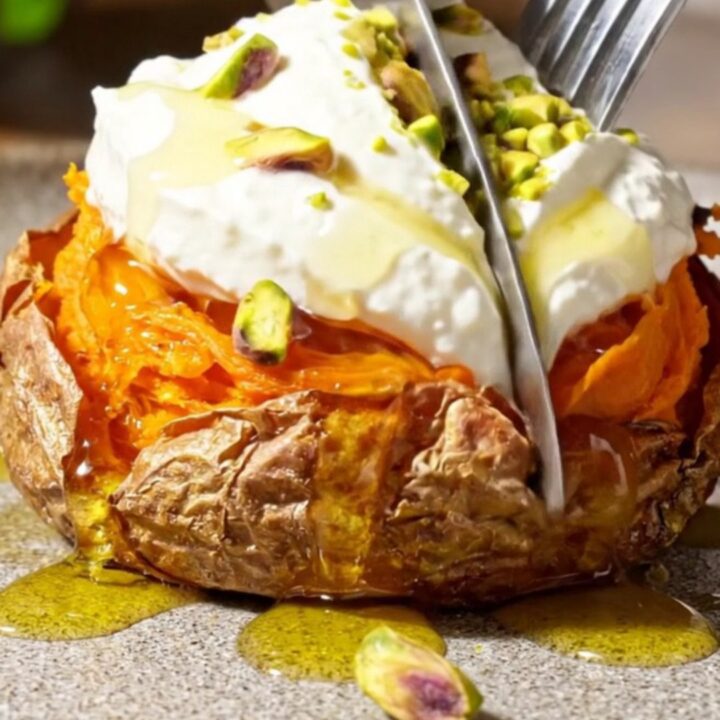 Crispy smashed sweet potato rounds topped with creamy whipped feta, hot honey, and crushed pistachios on a serving platter.