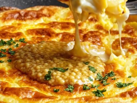 A golden, thick slice of Tortilla Española on a wooden board showing a creamy potato center.