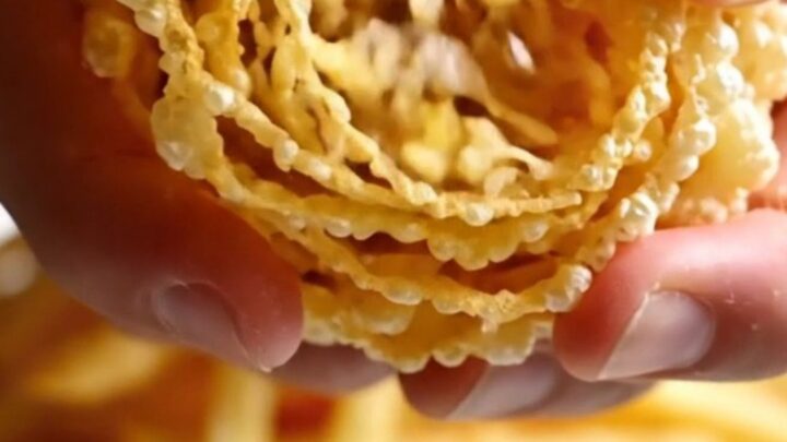 A mountain of golden, ultra-thin crispy potato and leek matchstick frites piled high on a dark plate.