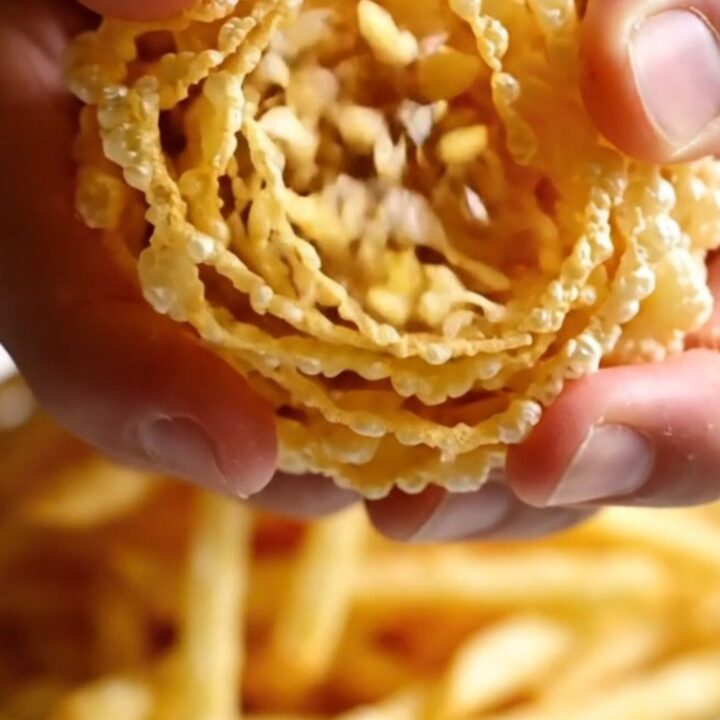 A mountain of golden, ultra-thin crispy potato and leek matchstick frites piled high on a dark plate.