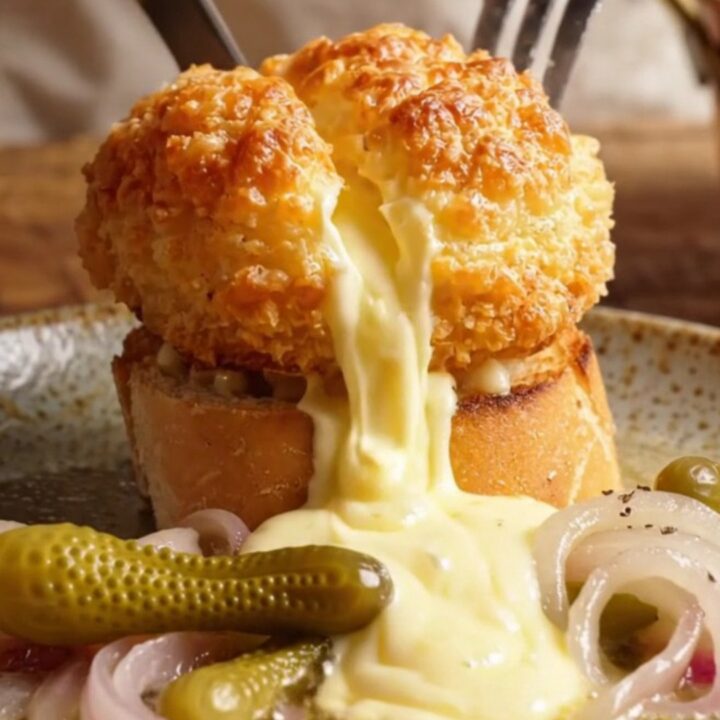 A close-up of a golden, crispy Swiss Malakoff dome on a toasted baguette