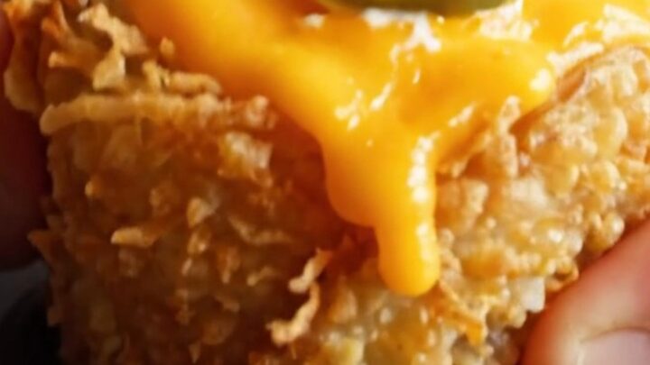 A close-up shot of a golden, crispy potato nest filled with molten cheese, bacon, and jalapeno, topped with cilantro.
