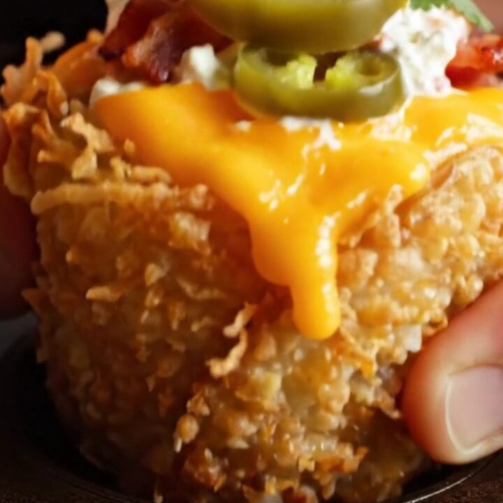 A close-up shot of a golden, crispy potato nest filled with molten cheese, bacon, and jalapeno, topped with cilantro.