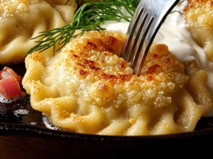 Crispy golden-brown pan-seared pierogi topped with crispy bacon bits, a dollop of sour cream